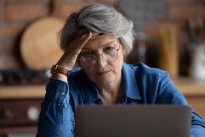 Mature woman looking confused while using laptop usage