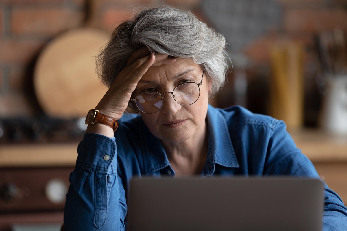 Mature woman looking confused while using laptop usage