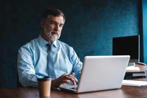 Mature Man Working On Computer In Office