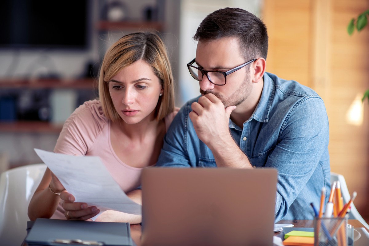 family managing budget, reviewing their bank accounts using laptop in kitchen