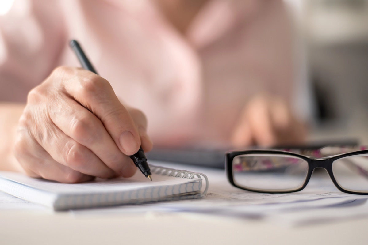 pension calculation concept, old hands counting finances on a home calculator , close- up